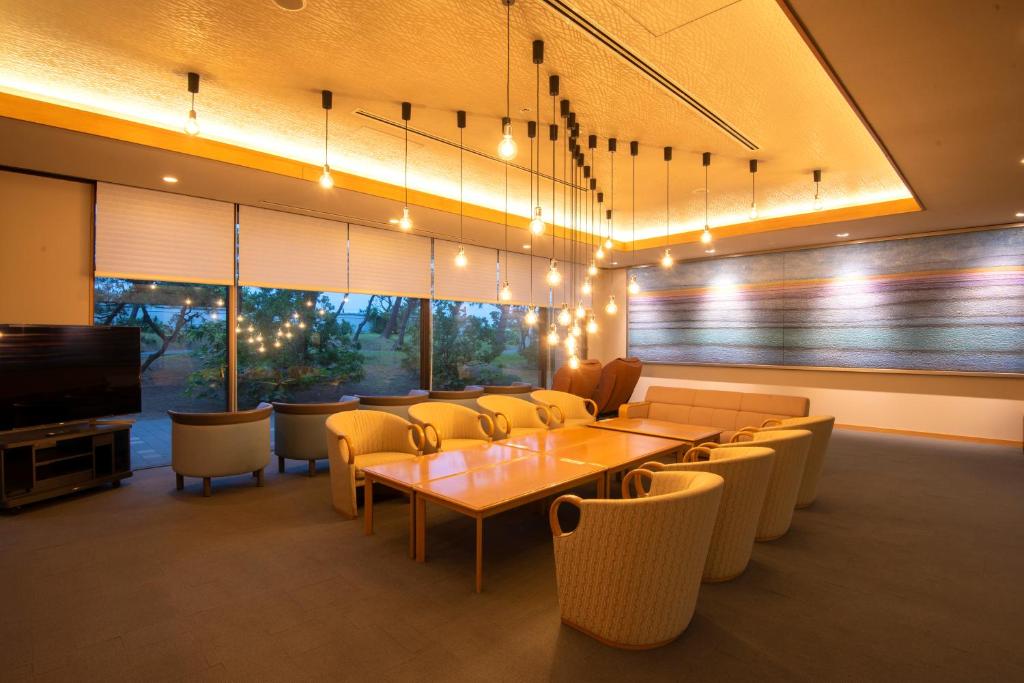 une salle à manger avec une table, des chaises et une télévision dans l'établissement KKR Numazu Hamayu, à Numazu