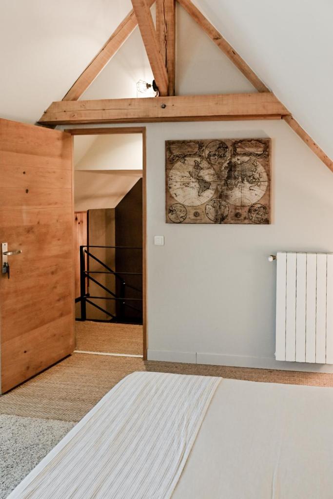 Cette chambre est dotée d'un mur blanc et d'une porte en bois. dans l'établissement Gîte Un ange passe en Périgord, au Buisson de Cadouin