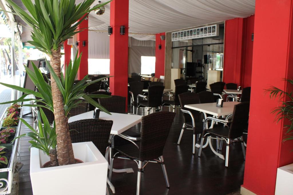 un restaurant avec des tables, des chaises et des palmiers dans l'établissement Hotel AMALFI, à Lido di Jesolo