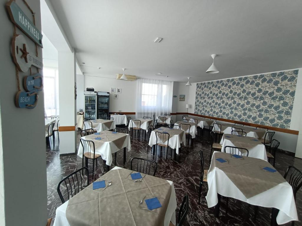une salle à manger avec des tables et des chaises blanches dans l'établissement Hotel La Torre, à Cervia