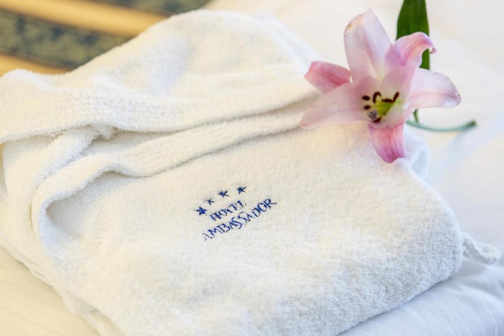 - une serviette blanche avec une fleur rose dans l'établissement Hotel Ambassador, à Tortoreto Lido