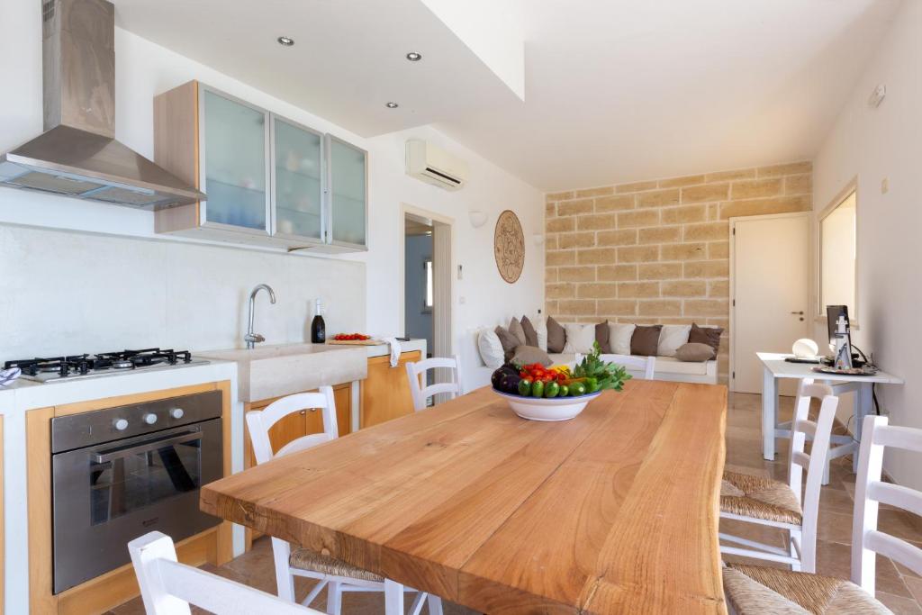 Il comprend une cuisine et un salon avec une table en bois. dans l'établissement VILLA BIANCA con piscina e vista mare, à Gagliano del Capo