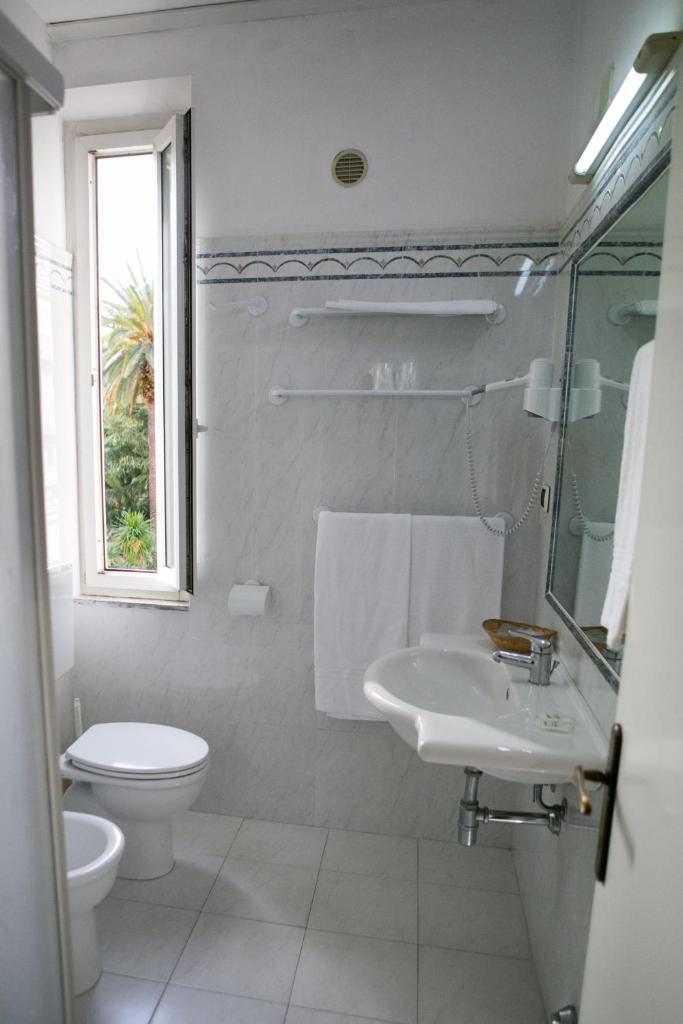une salle de bain blanche avec toilettes et lavabo dans l'établissement Hotel Giardino, à Follonica
