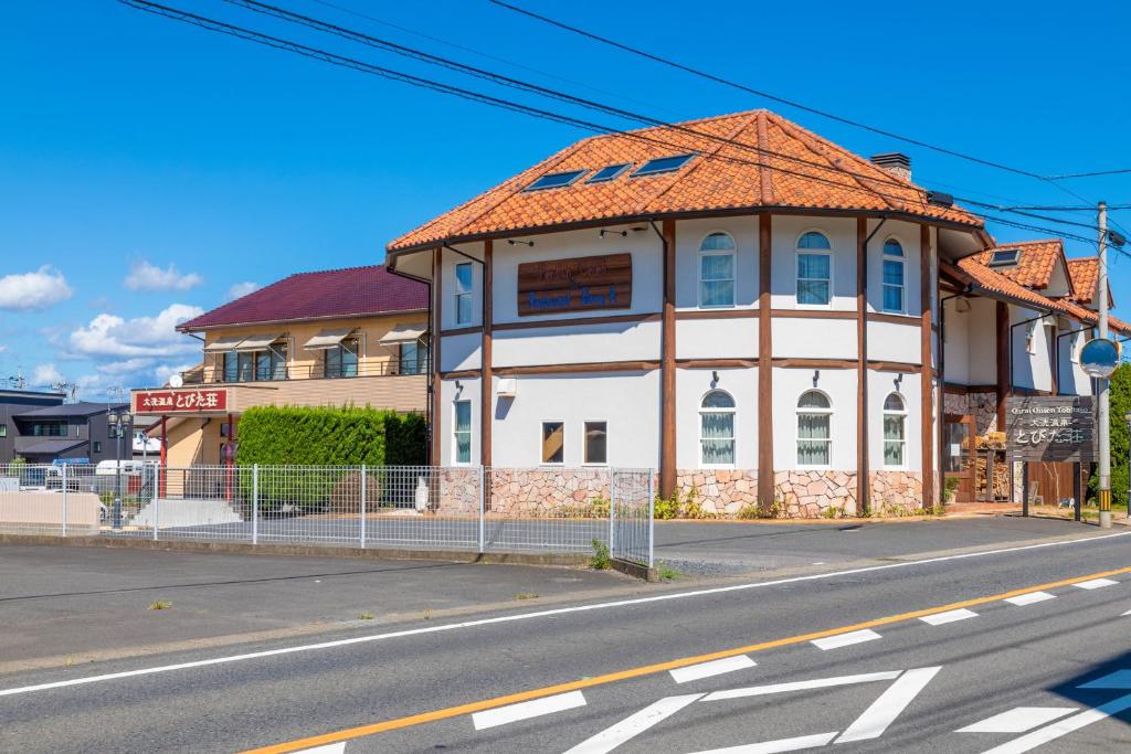 un bâtiment blanc avec un toit orange dans une rue dans l'établissement とびた荘 #小学生以下は宿泊不可#, à Ōarai