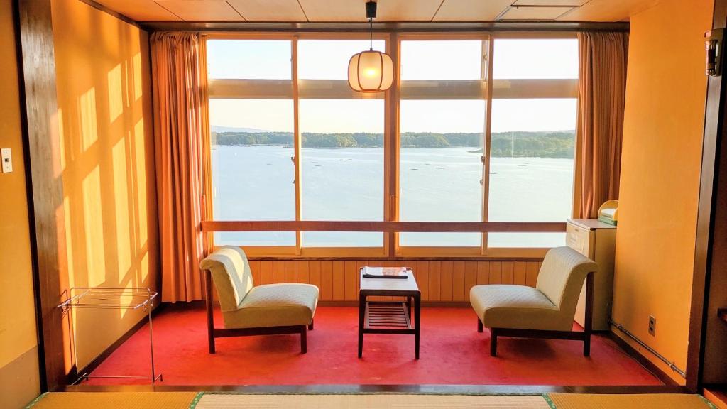 une chambre avec deux chaises, une table et une grande fenêtre dans l'établissement Aokiya, à Sado