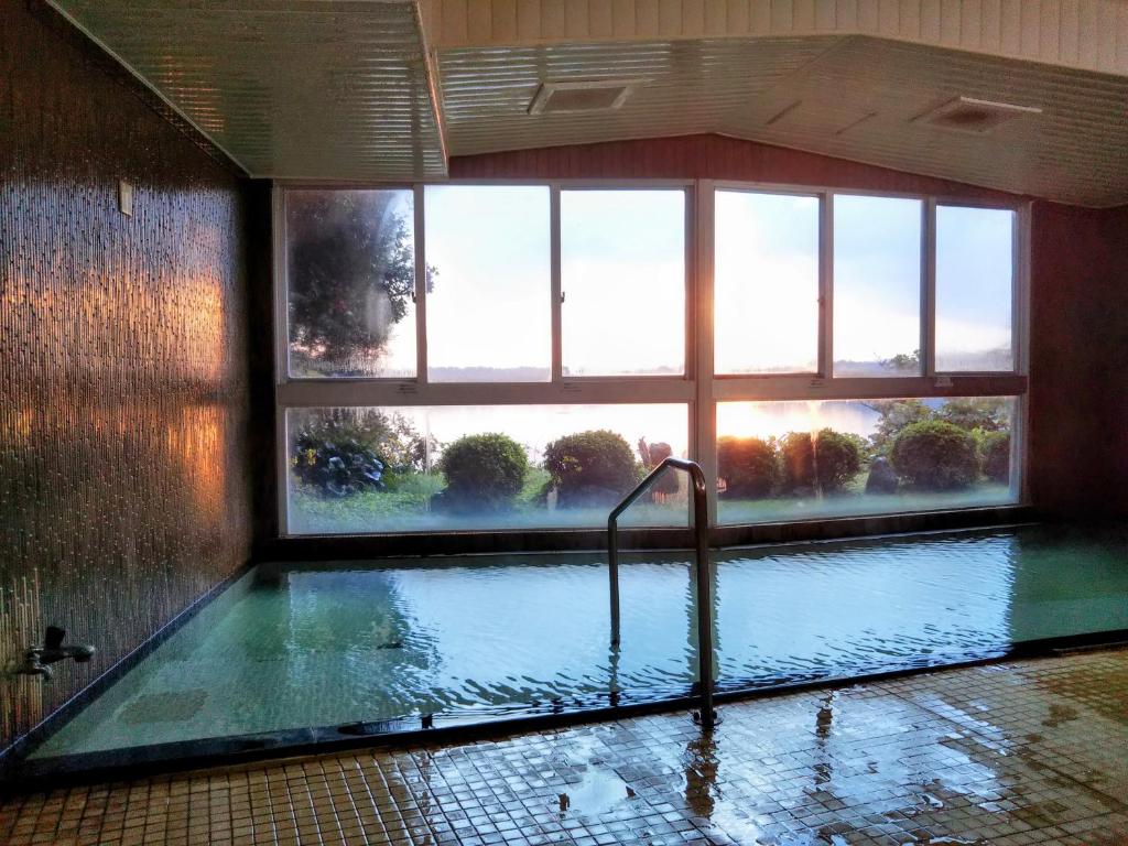une grande piscine dans une pièce avec une fenêtre dans l'établissement Aokiya, à Sado