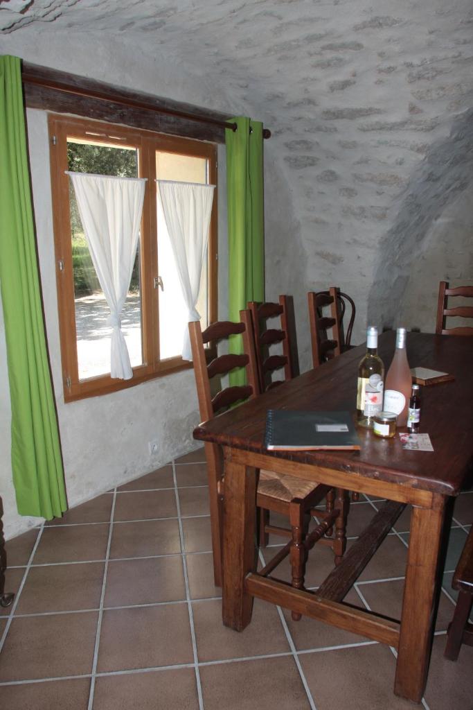 une salle à manger avec une table et des chaises et une fenêtre dans l'établissement Le Mas Draiou Ecogites - 2 gites et une chbre familliale combinables 14 pers, à Saint-Restitut