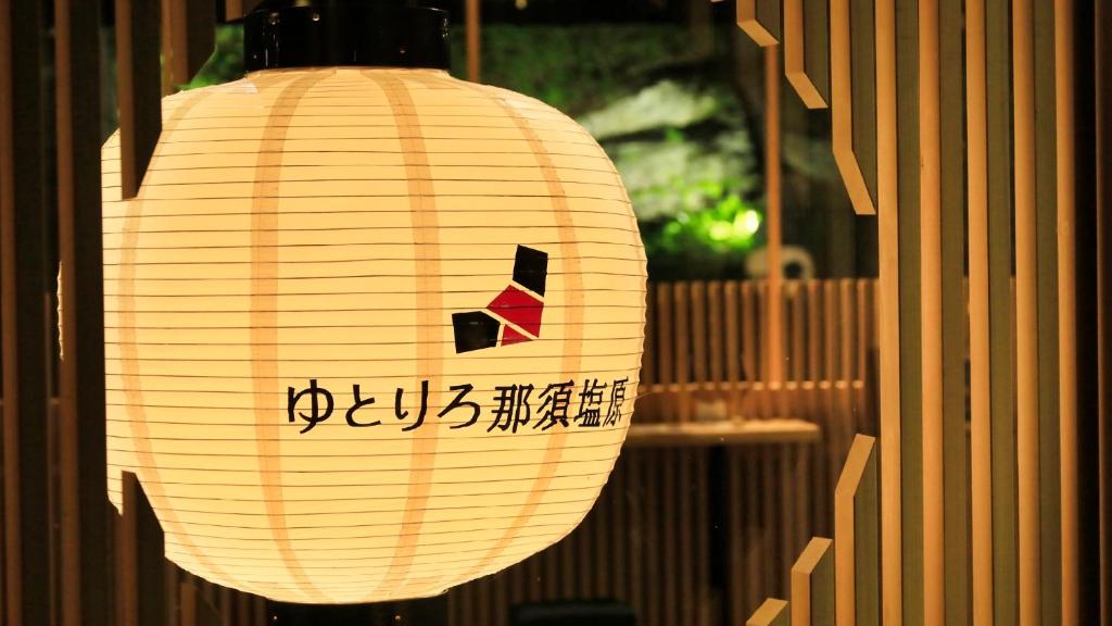 une lanterne en papier avec une écriture dessus suspendue à un bâtiment dans l'établissement Yutorelo Nasushiobara, à Nasushiobara