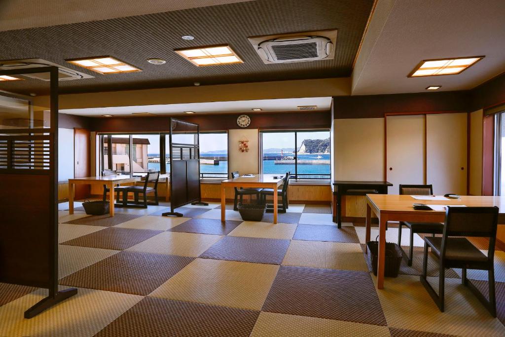 - un restaurant avec des tables et des chaises et une vue sur l'eau dans l'établissement Uminoniwa, à Kamogawa