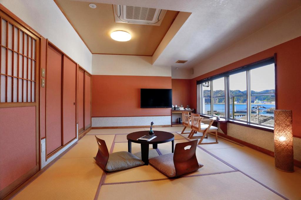 une pièce avec une table, des chaises et une télévision dans l'établissement Uminoniwa, à Kamogawa