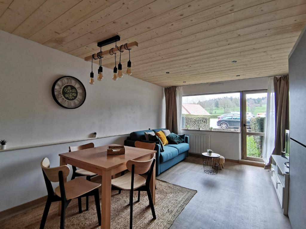 un salon avec une table et un canapé bleu dans l'établissement L'échappée étoilée - Métabief, à Métabief