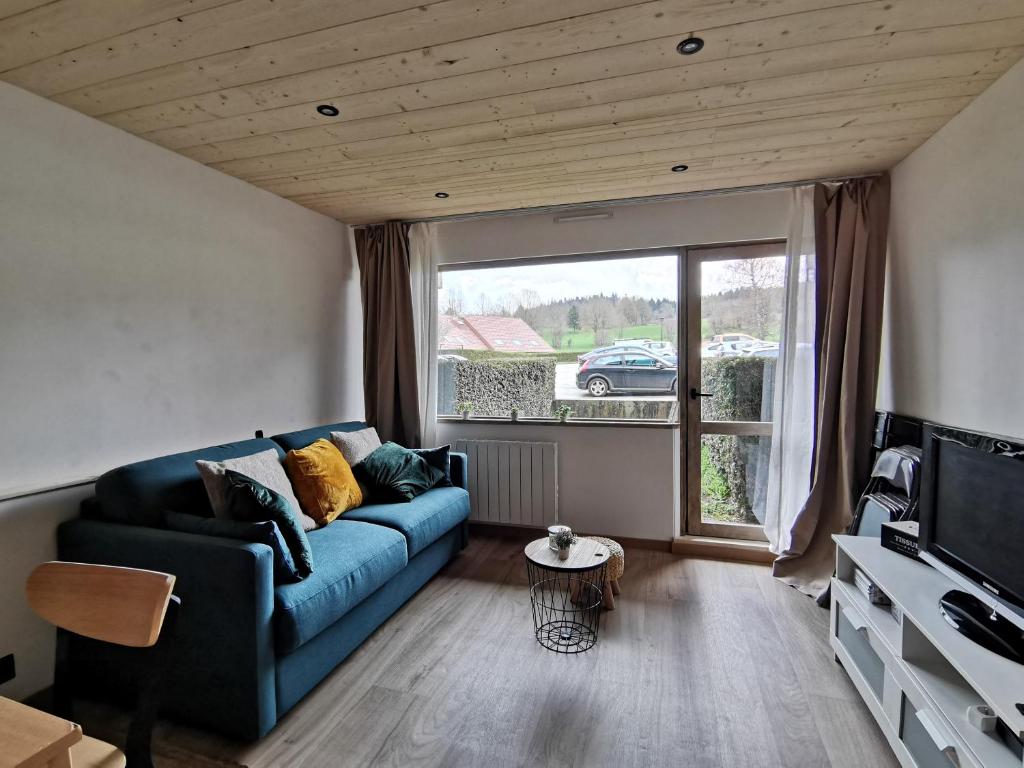 un salon avec un canapé bleu et une fenêtre dans l'établissement L'échappée étoilée - Métabief, à Métabief