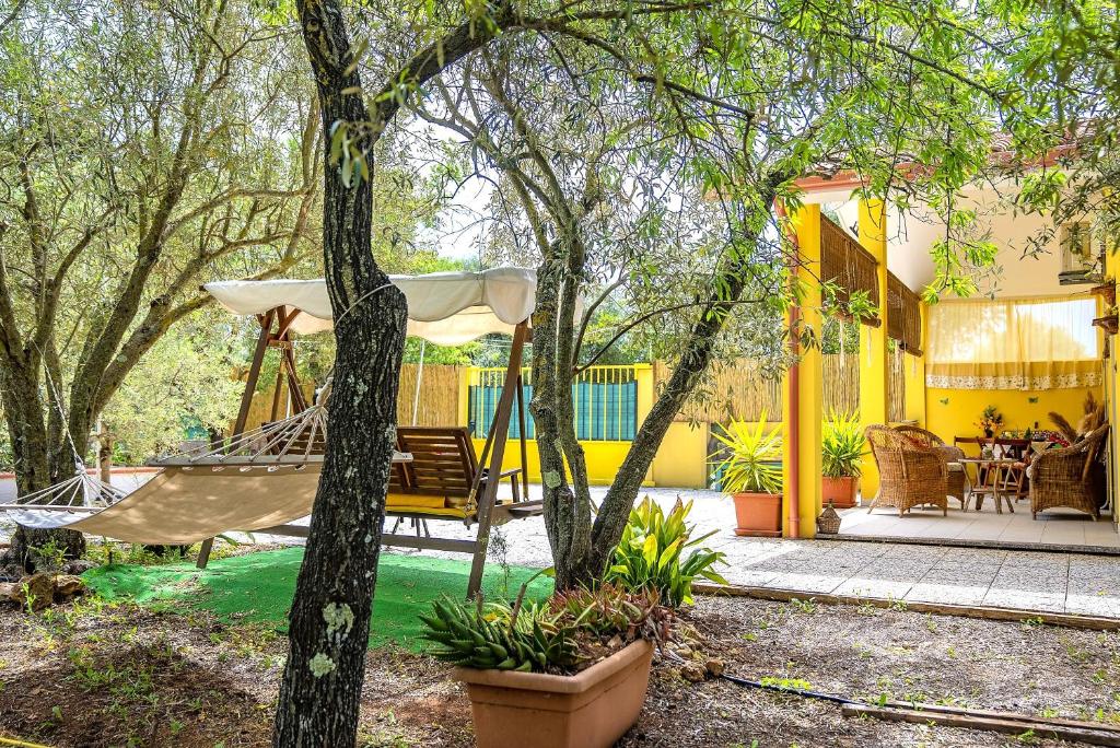 - un hamac dans une cour avec une maison jaune dans l'établissement Villa Ottavio - SHARDAN-APARTMENTS, à Iglesias
