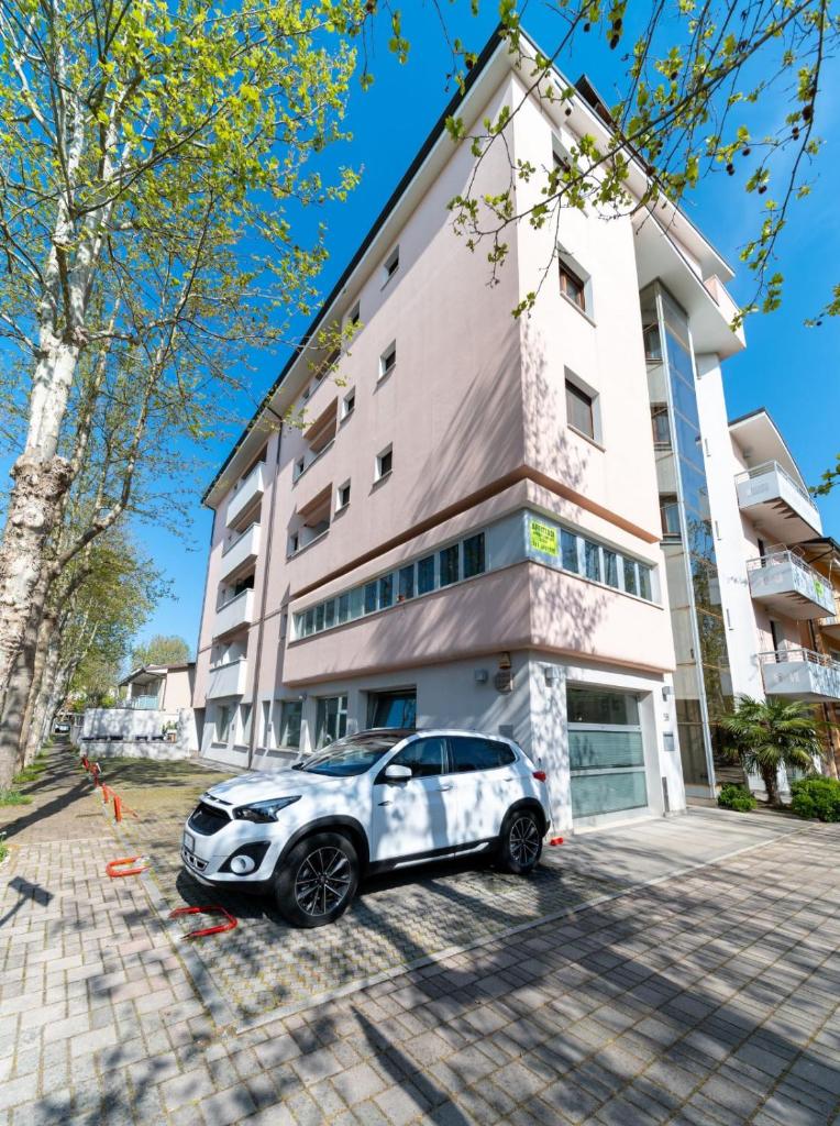 une voiture blanche garée devant un immeuble dans l'établissement Residence Alessandra, à Cesenatico