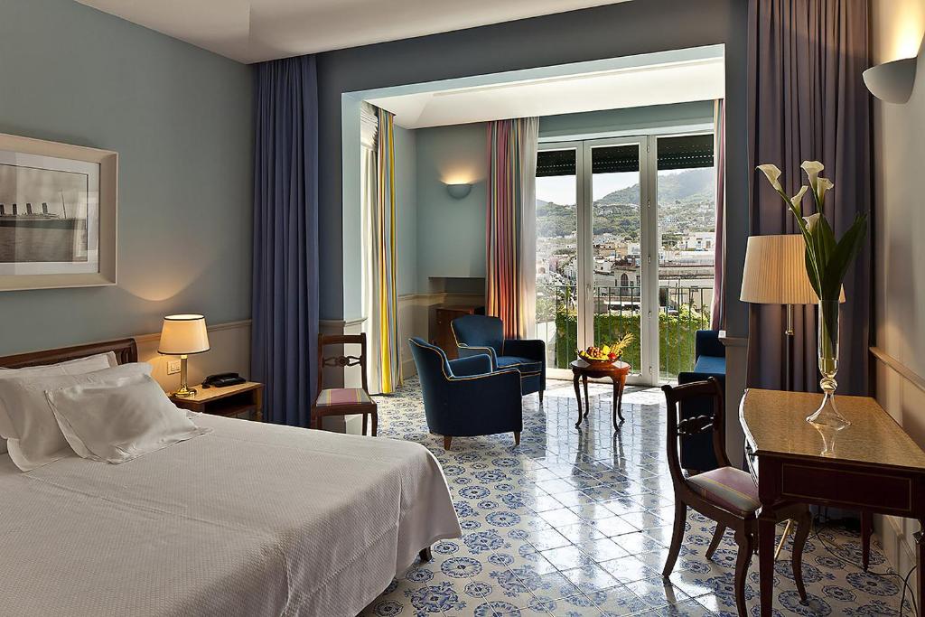 une chambre d'hôtel avec un lit, un bureau et des chaises dans l'établissement Regina Isabella-Resort Spa Restaurant, à Ischia