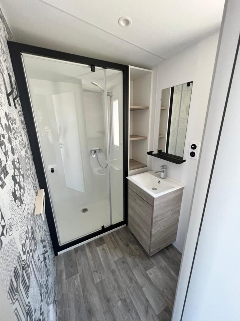 une salle de bain avec une douche, un lavabo et un miroir dans l'établissement Mobile Evasion okpl BEAUVOIR, à Saint-Raphaël