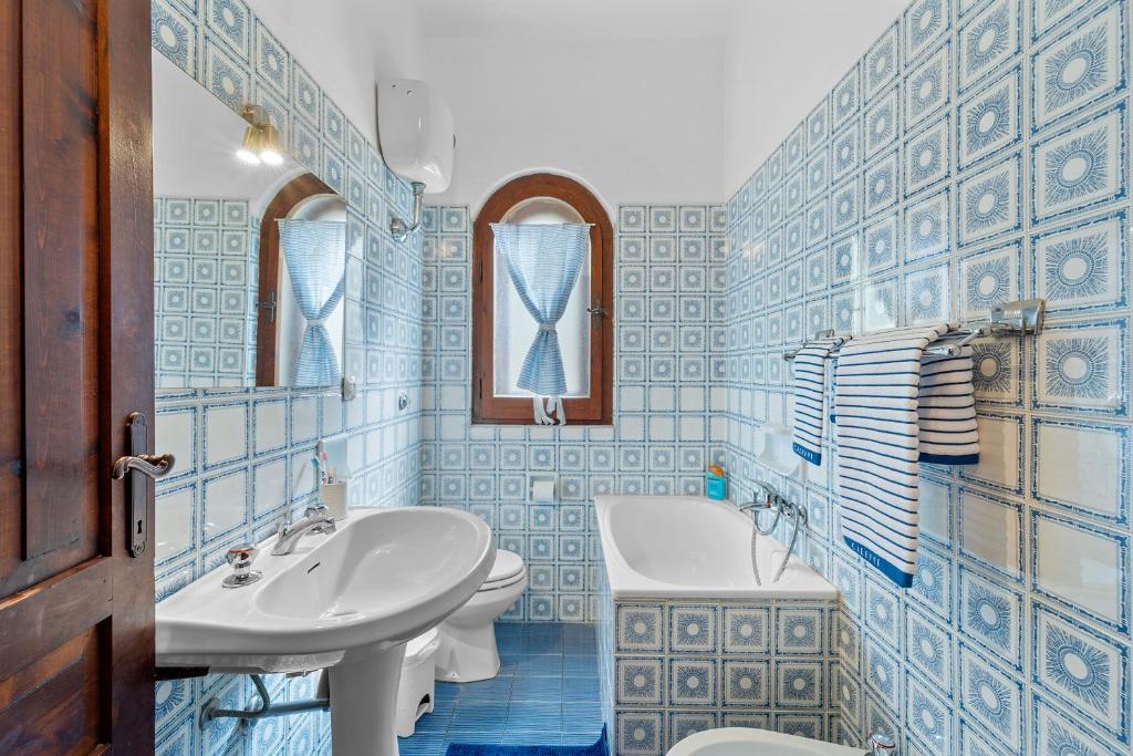 La salle de bains est pourvue de carrelage bleu, d'un lavabo et de toilettes. dans l'établissement Villa Viola, à Torre delle Stelle