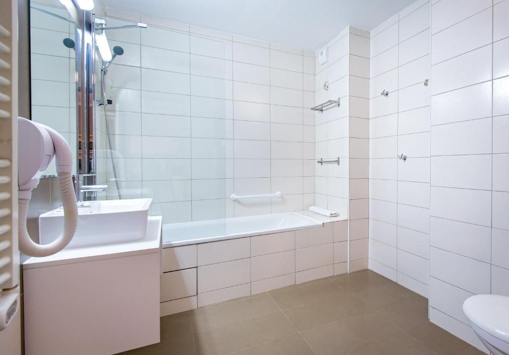 une salle de bain blanche avec une baignoire et un lavabo dans l'établissement SOWELL RESIDENCES New Chastillon, à Isola 2000