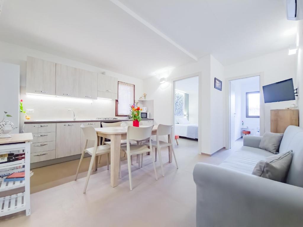 Il dispose d'une cuisine blanche et d'un salon avec une table et des chaises. dans l'établissement Villetta Oasi nelle Rocce con Piscina Privata, à Acquarica del Capo 16 autres photos