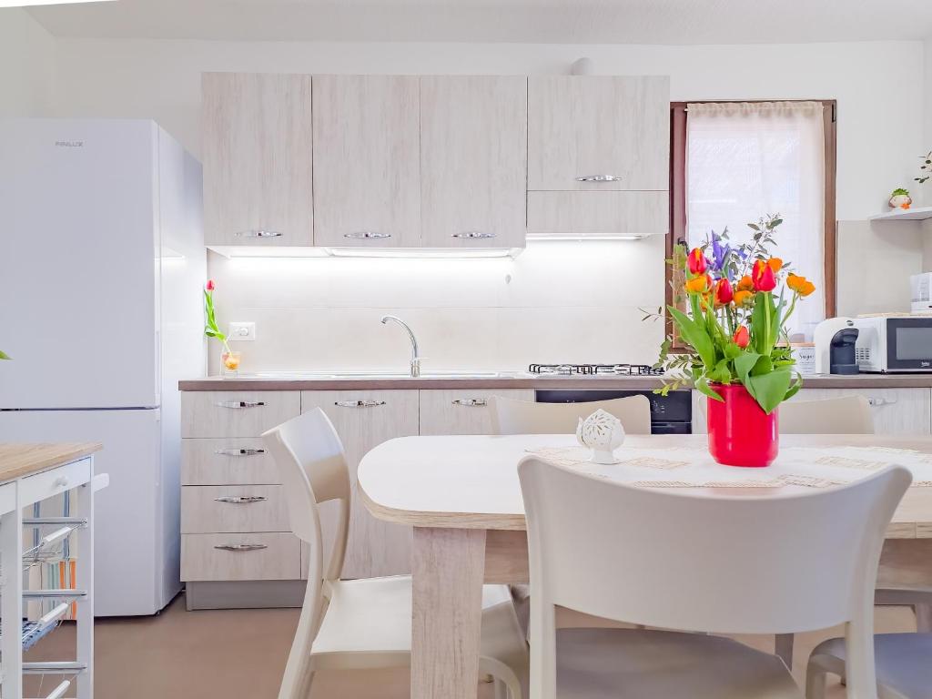 - une cuisine avec une table blanche, des chaises et des fleurs blanches dans l'établissement Villetta Oasi nelle Rocce con Piscina Privata, à Acquarica del Capo
