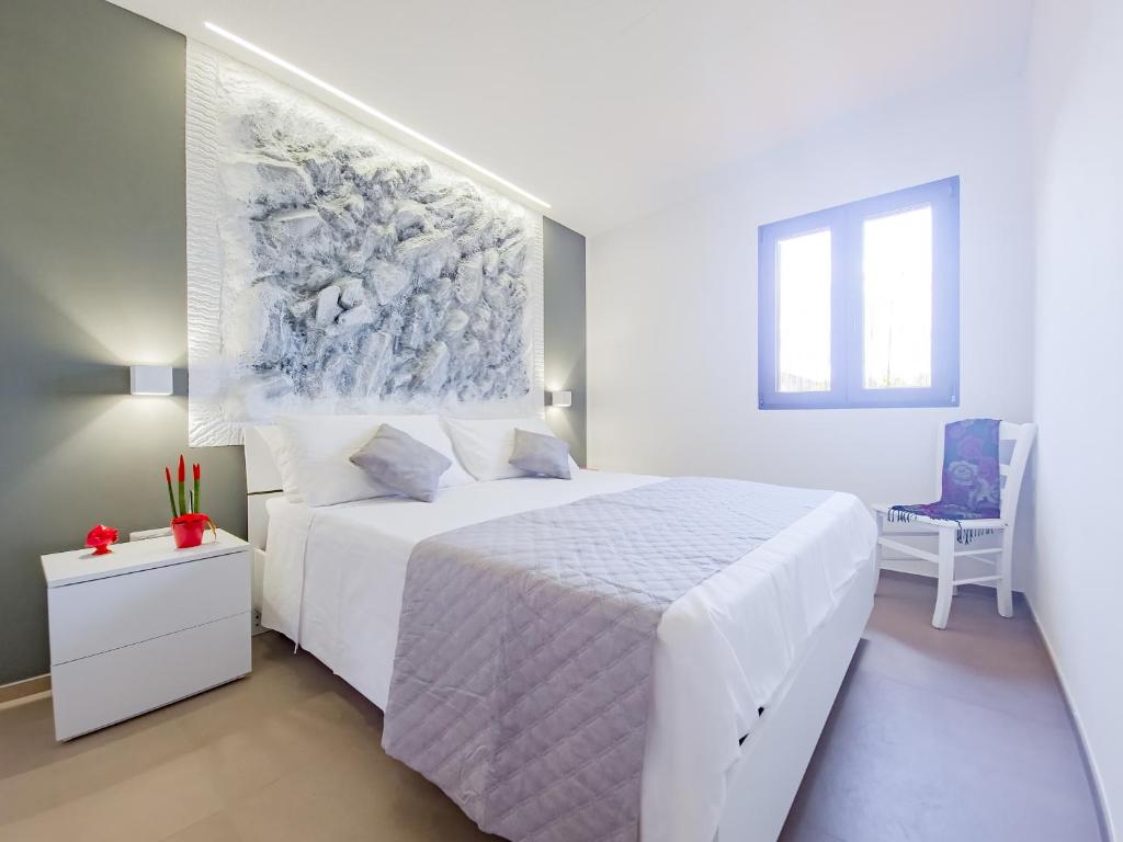 - une chambre blanche avec un lit blanc et un tableau mural dans l'établissement Villetta Oasi nelle Rocce con Piscina Privata, à Acquarica del Capo