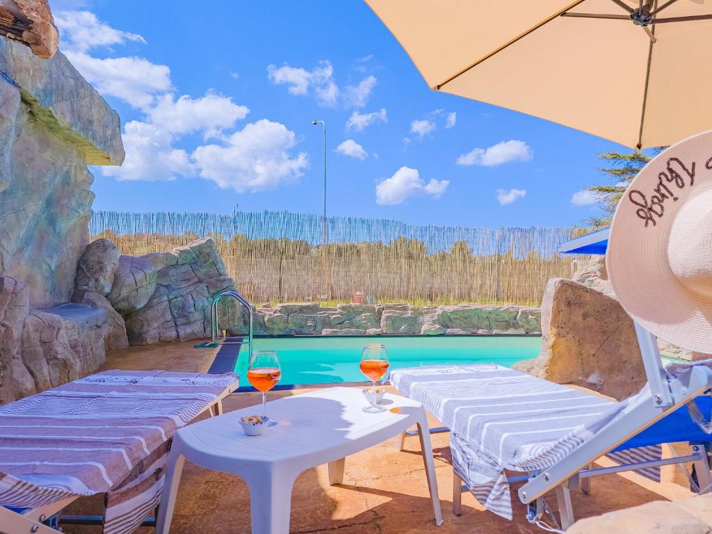 - une piscine avec 2 chaises longues et un parasol dans l'établissement Villetta Oasi nelle Rocce con Piscina Privata, à Acquarica del Capo