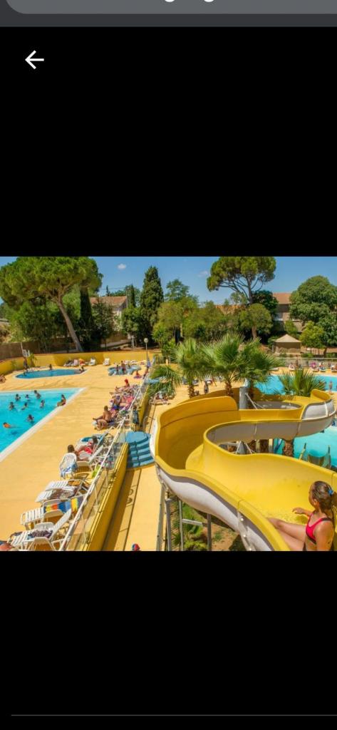 - une piscine avec des chaises et des personnes dans un complexe dans l'établissement Camping parc les 7 fonts, à Agde