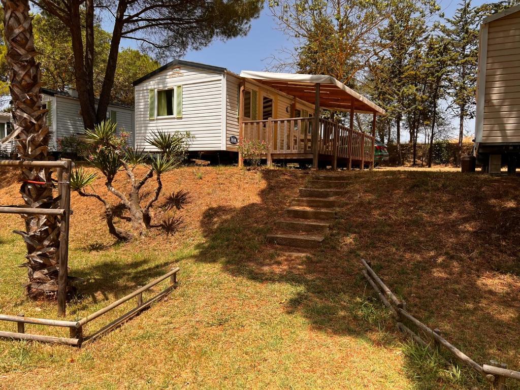une petite maison avec une terrasse couverte et des escaliers. dans l'établissement Camping parc les 7 fonts, à Agde