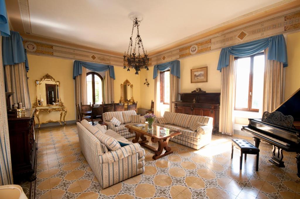 un salon avec des canapés et un piano dans l'établissement Villa Pieroni - Barga, à Castelvecchio Pascoli
