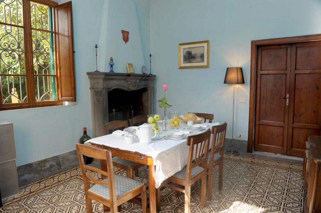 une salle à manger avec une table, des chaises et une cheminée dans l'établissement Villa Pieroni - Barga, à Castelvecchio Pascoli