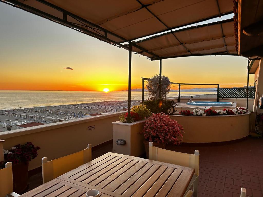 un patio avec une table et un coucher de soleil sur la plage dans l'établissement Piccadilly Penthouse with Jacuzzi, à Lido di Camaiore