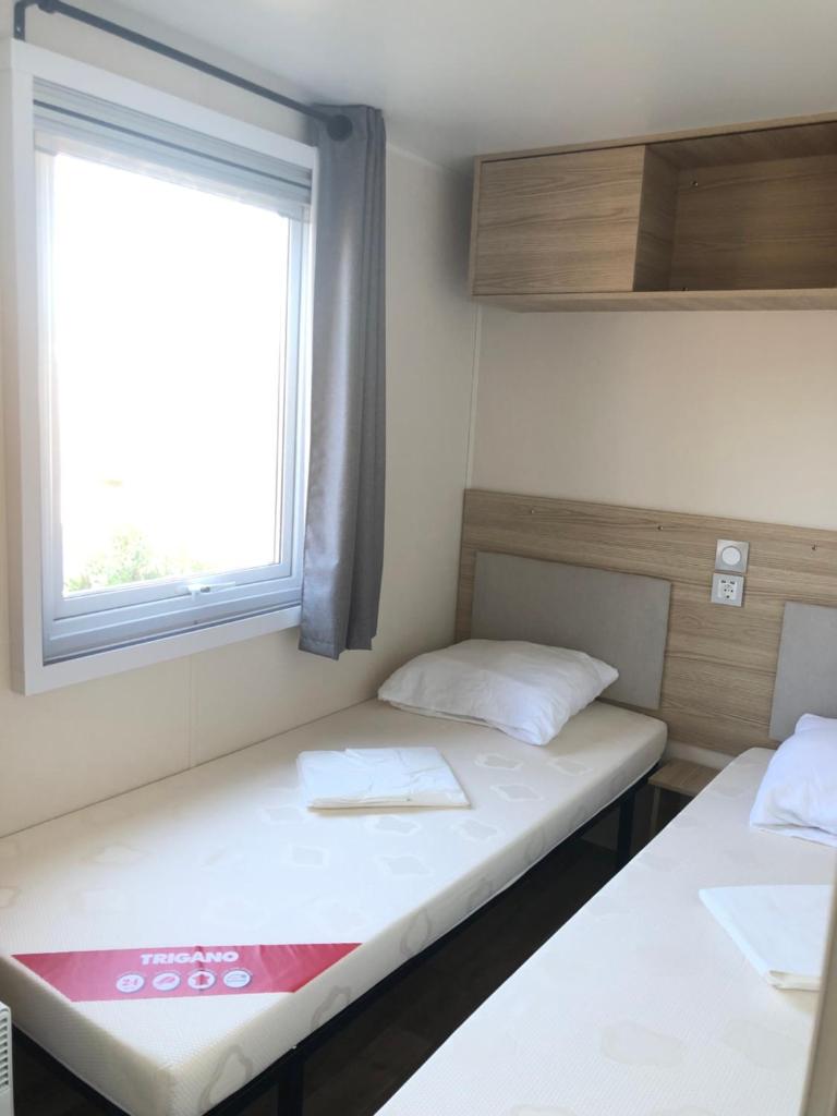 deux lits dans une petite pièce avec une fenêtre dans l'établissement Azur, à Fréjus 9 autres photos