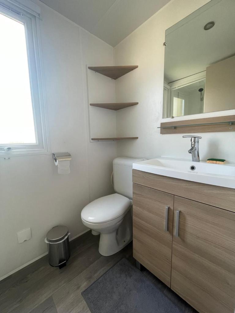 une salle de bain avec toilettes, lavabo et miroir dans l'établissement Mobil home luxe 8 personnes avec wifi, à Onzain 9 autres photos