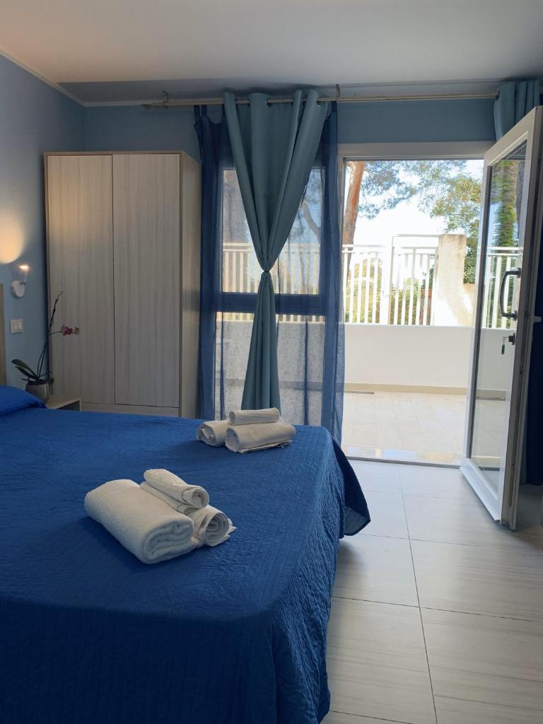 une chambre avec deux serviettes sur un lit bleu dans l'établissement HOTEL MERCURIO SUL MARE - Fish restaurant and private beach, à Capo Vaticano