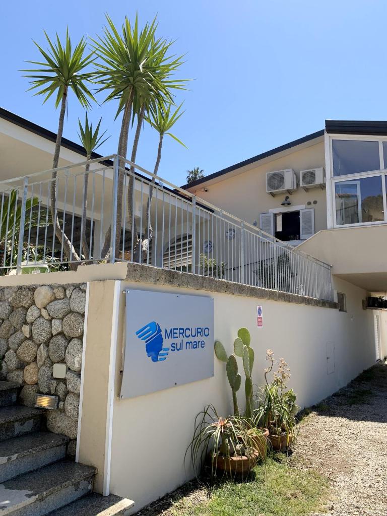 - un panneau de bienvenue devant un bâtiment avec des palmiers dans l'établissement HOTEL MERCURIO SUL MARE - Fish restaurant and private beach, à Capo Vaticano