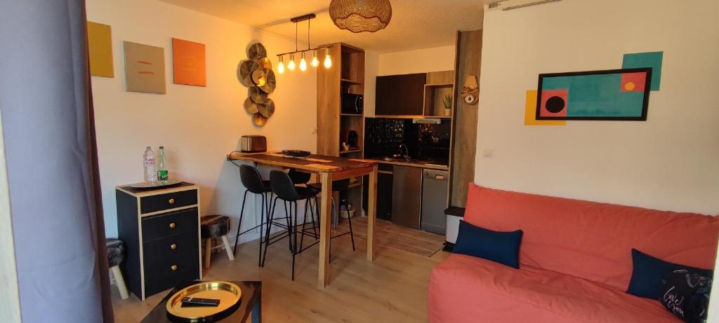 un salon avec un canapé rouge et une cuisine dans l'établissement Orcières Rond point des Pistes, Front de neige, à Orcières