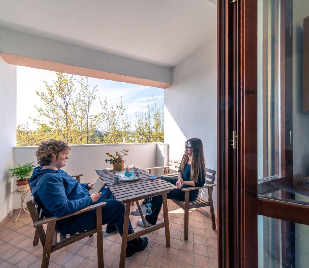 deux personnes assises à une table sur un balcon dans l'établissement Residence Alessandra, à Cesenatico