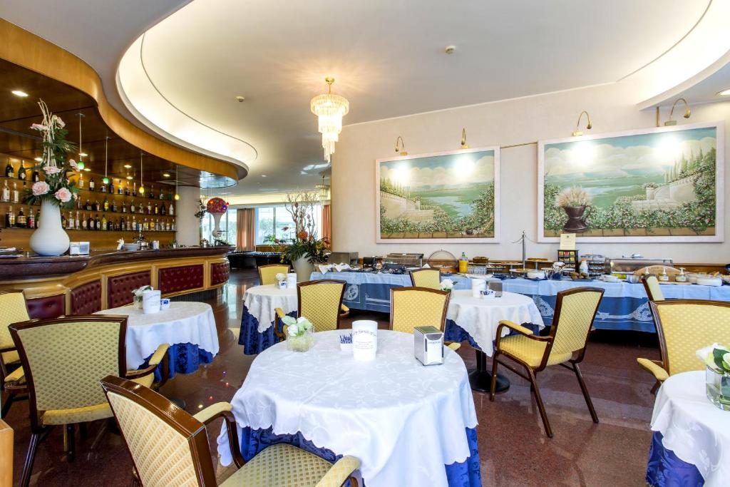 une salle à manger avec des tables et des chaises blanches dans l'établissement Hotel Ambassador, à Tortoreto Lido