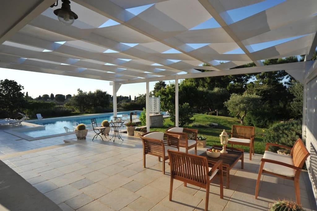 une terrasse avec des chaises, une table et une piscine dans l'établissement CASA NEL VERDE CON GIARDINO E PISCINA PRIVATA, à Polignano a Mare
