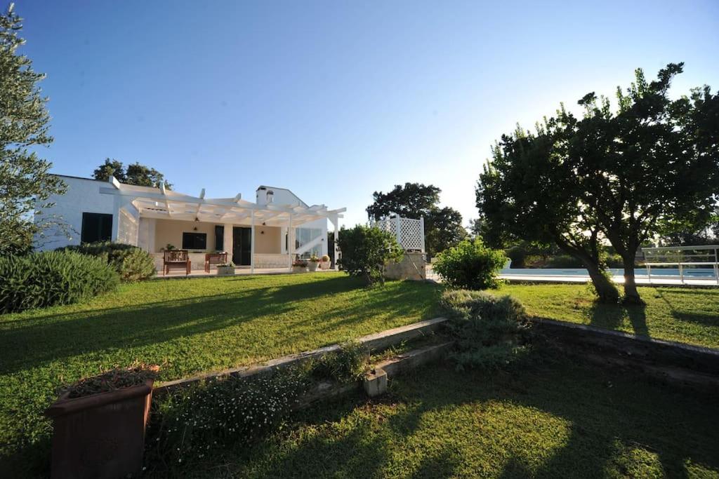 une cour avec une maison blanche et un arbre dans l'établissement CASA NEL VERDE CON GIARDINO E PISCINA PRIVATA, à Polignano a Mare