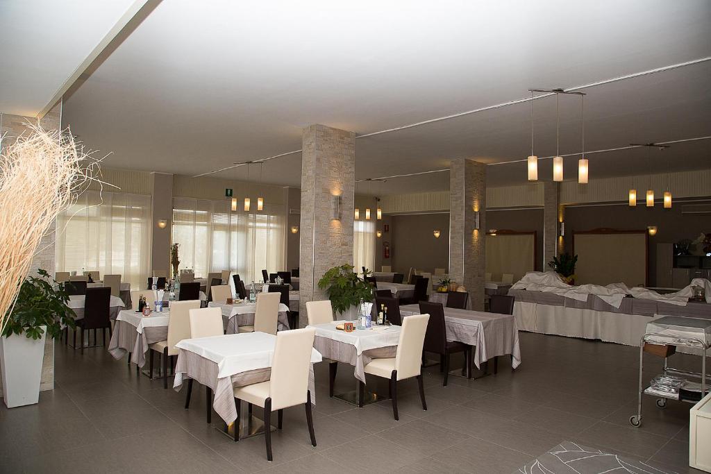 une salle à manger avec des tables et des chaises blanches dans l'établissement Hotel Umberto, à Rosolina Mare