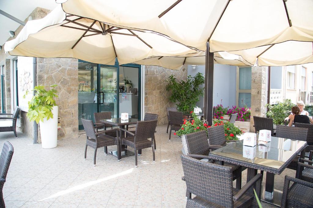 une terrasse extérieure avec tables et chaises et parasols dans l'établissement Hotel Umberto, à Rosolina Mare