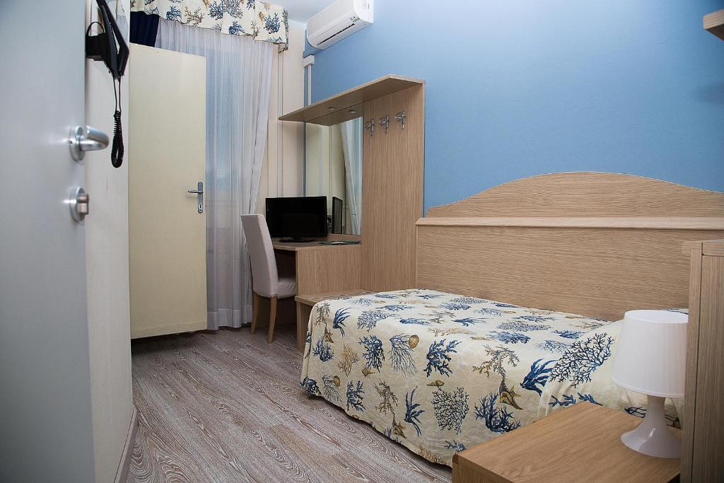 une chambre avec un lit et un bureau avec un ordinateur dans l'établissement Hotel Umberto, à Rosolina Mare