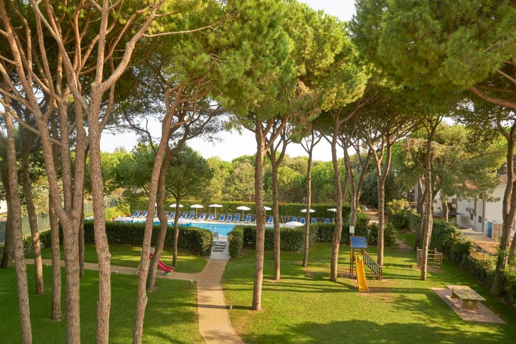 - une vue sur un parc avec une piscine et des arbres dans l'établissement Aparthotel La Pineta, à Lido di Jesolo