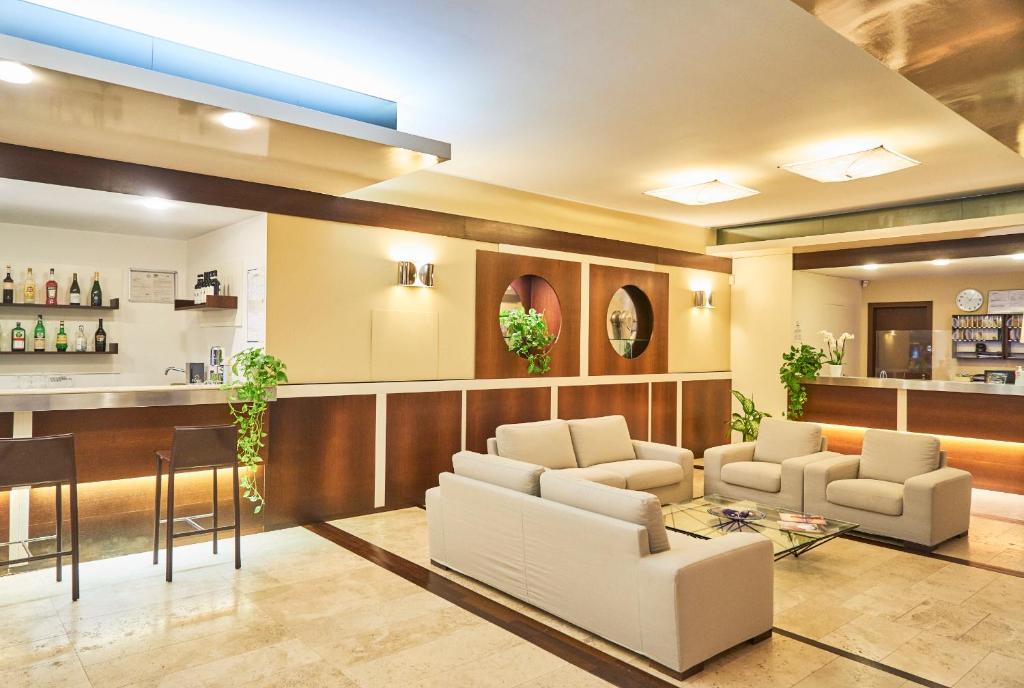 un hall avec des chaises blanches et un bar dans l'établissement Aparthotel La Pineta, à Lido di Jesolo