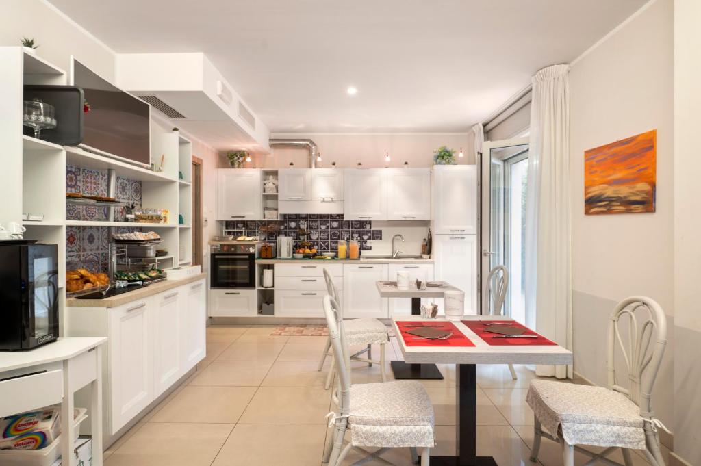 une cuisine avec des armoires blanches et une table et des chaises dans l'établissement Echotel, à Porto Recanati 17 autres photos