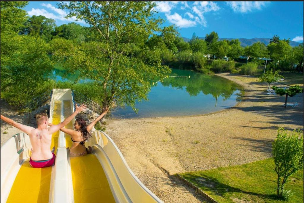 deux personnes sur des montagnes russes au bord d'un lac dans l'établissement Camping Domaine des Iscles, à La Roque-dʼAnthéron