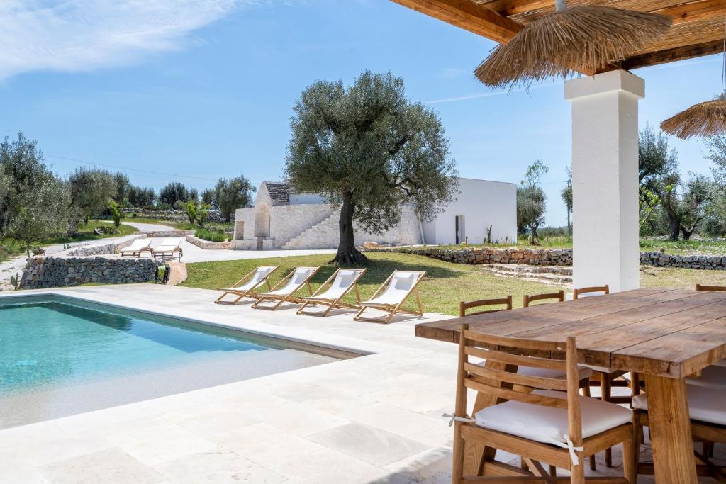 une terrasse avec une table et des chaises en bois à côté d'une piscine dans l'établissement Trulli Cicerali , trulli design con piscina panoramica, à Ostuni