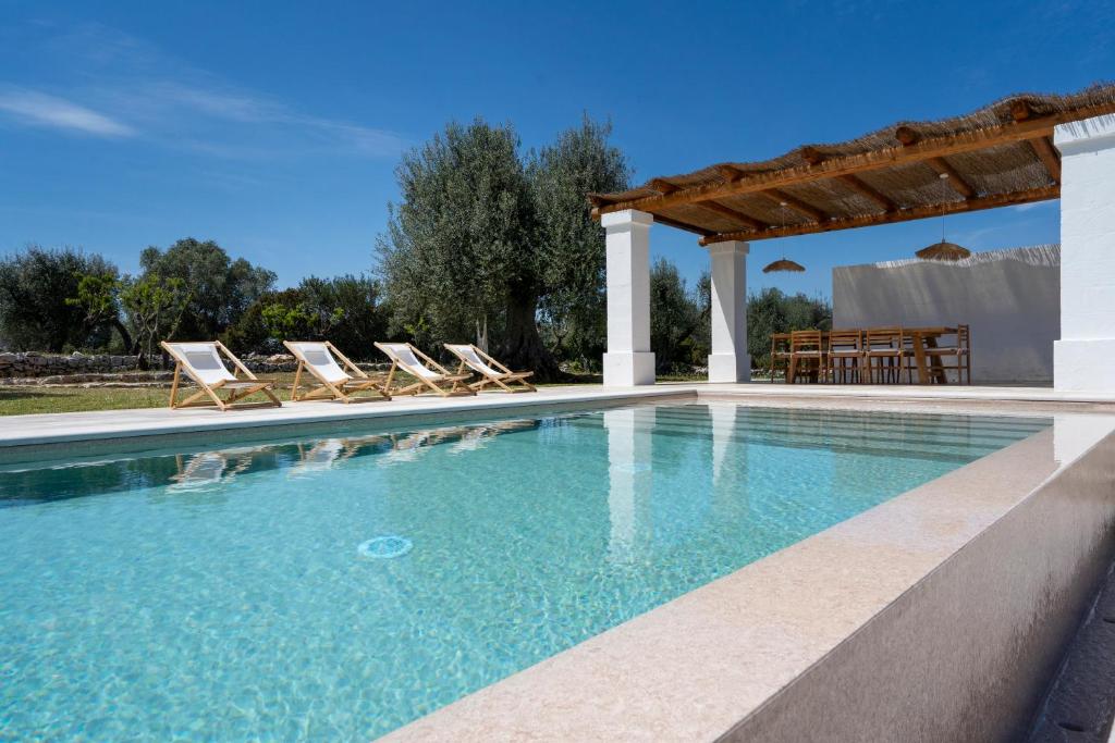 une piscine avec des chaises et un gazebo dans l'établissement Trulli Cicerali , trulli design con piscina panoramica, à Ostuni