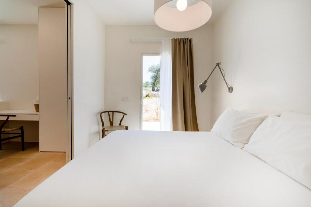 une chambre avec un lit blanc et un bureau dans l'établissement Trulli Cicerali , trulli design con piscina panoramica, à Ostuni